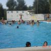 Persone che nuotano e si divertono in una piscina all'aperto con un murales.
