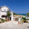 Edificio bianco su una collina con vista sul mare e piscina con ombrelloni arancioni.