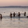 Persone che giocano in acqua al tramonto con una palla rossa.