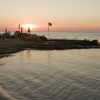 Tramonto su una spiaggia con ombrelloni e una bandiera.