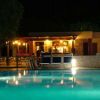 Piscina illuminata di notte, con un bar in pietra sullo sfondo.