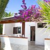 Bungalow bianco con bouganville fiorita e palme.