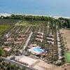Complesso residenziale con piscina, circondato da ulivi e campi coltivati vicino al mare.